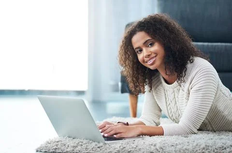 Settling down with a good read. Shot of a young woman using her laptop while Foto stock
