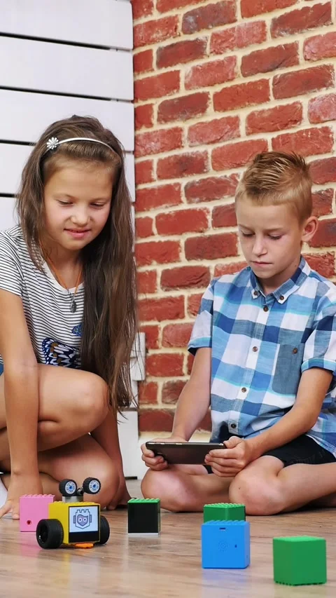 Seven-year-old boy and girl play electronic robots, cars, modern toys on the Stock Footage 314790557