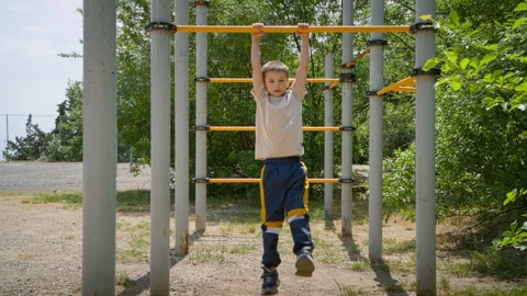 A seven-year-old boy can be seen pulling himself up on a horizontal bar. Stock Footage 274420898