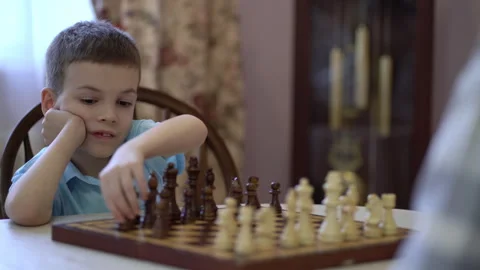 A seven-year-old boy plays chess with his mother at home at the table. Stock Footage 241098774