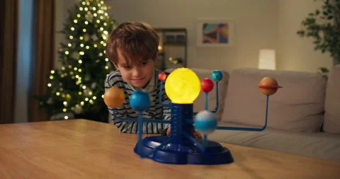 A seven-year-old boy is studying the planets. In front of him on the table is 스톡 동영상 210491643