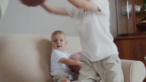 Seven year old boy throwing pillow back at mother during fun game Stock Footage 316578541