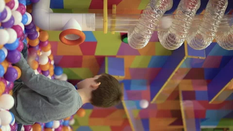 A seven-year-old child puts plastic balls into an air tube while playing in the Stock Footage 229986271