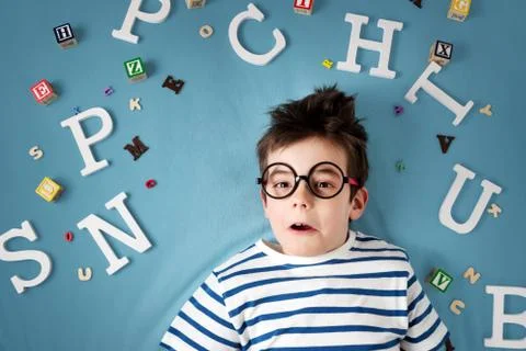 Seven years old child lying with glasses and letters Stock Photos
