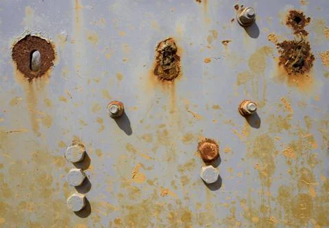 Several areas of rust and rusting bolts on a grey metal surface background. Stock Photos