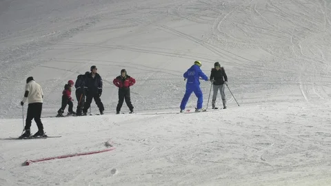 Several awkward tourists training with the instructor how to ski in snowy winter Stock Footage 123087699