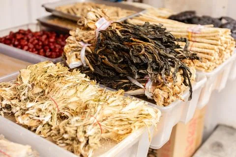 Several baskets are filled with dried herbs and roots at a market. Nearby, .. Stock Photos