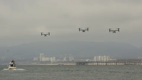 Several bell Boeing V-22 Osprey helicopters fly over the beautiful ocean coast. Stock Footage 106325500