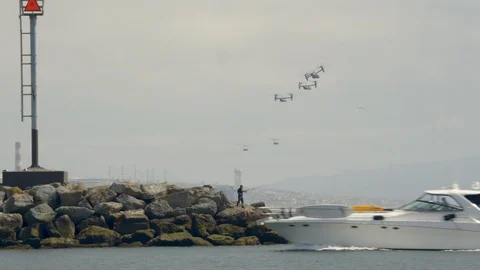 Several bell Boeing V-22 Osprey helicopters fly over the beautiful ocean coast. Stock Footage 106338432