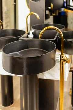 Several black round sinks stand on display in a modern bathroom. The sinks ha Foto stock