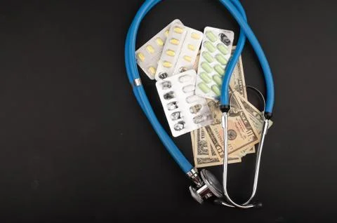 Several blisters with different tablets, a stethoscope, and dollar bills on a Stock Photos