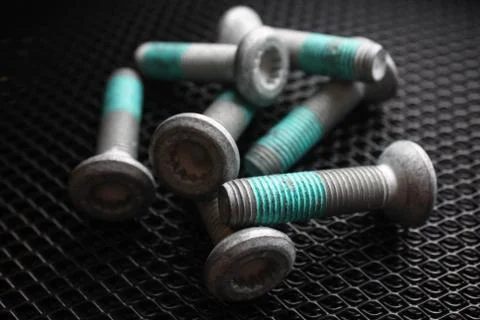 Several bolts covered with blue thread lock on dark background Stock Photos
