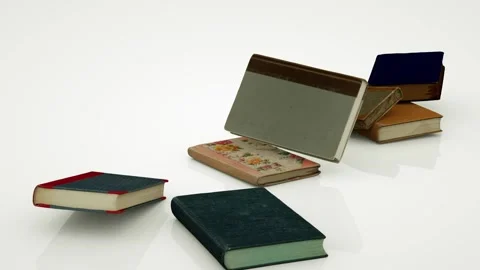 Several books fall right in front of the camera onto a white surface. Several Stock Footage 155179247