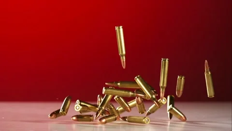 Several brass bullets fall from above and bounce across a white table. Stock Footage 326755666