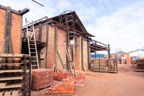 Several bricks are stacked on the outside of a building, in front of several woo Foto stock