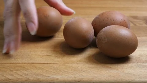 Several brown chicken eggs are placed on a wooden table. Close-up Stock Footage 346800460