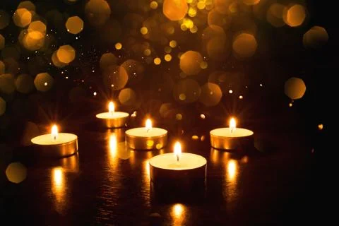 Several burning candles on a black background. Stock Photos