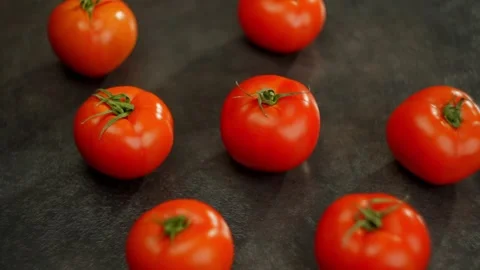 Several cherry tomatoes resting on a dark surface, part of a food recipe Stock Footage 267840281