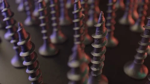 Several chrome-plated self-cutting screws are positioned tip up on the table Stock Footage 159550342