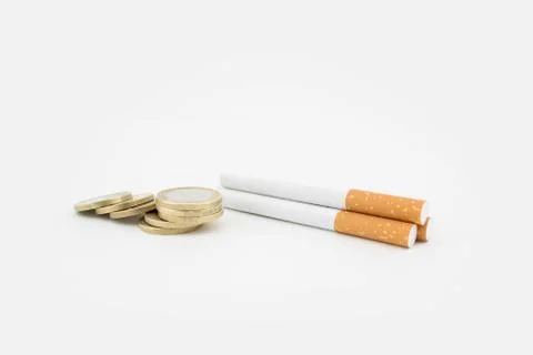 Several cigars and a stack of coins on white background. Economic expenditure Stock Photos