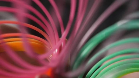 Several circles of a colorful plastic rainbow slinky moving cheery in slo-mo Stock Footage 101760121