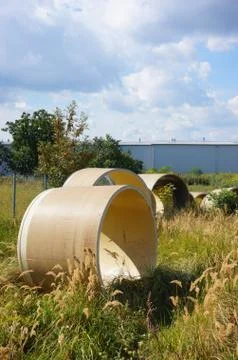 Several circular objects on a field of grass and trees behind a wall under a  Stock Photos