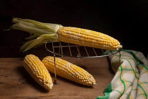 Several cobs sweet corn with green leaves on wooden background.. Stock Photos