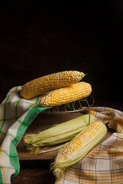 Several cobs sweet corn with green leaves on wooden background.. Stock Photos