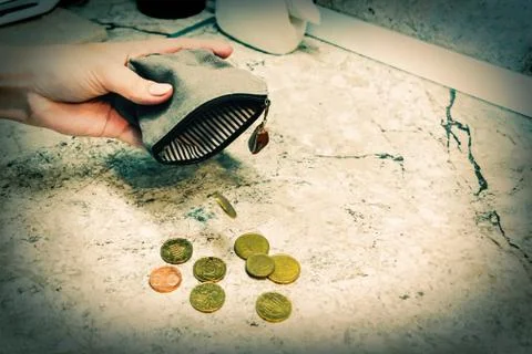 Several coins fall from an empty purse in a woman's hand Stock Photos