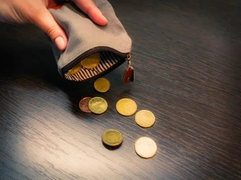 Several coins fall from an empty purse in a woman's hand Foto stock