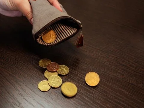 Several coins fall from an empty purse in a woman's hand Stock Photos