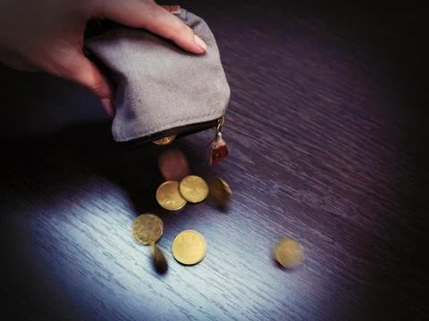 Several coins fall from an empty purse in a woman's hand Stock Photos