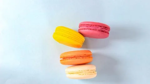 Several colored macarons on a blue background. Stock Photos