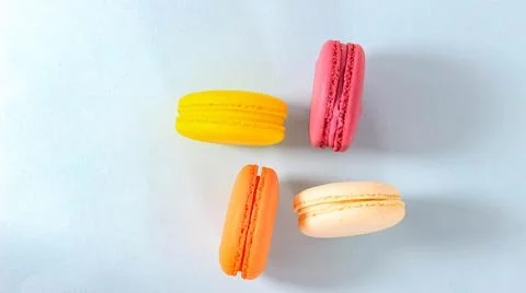 Several colored macarons on a blue background. Stock Photos