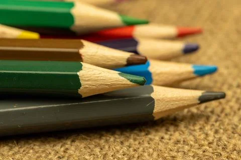 Several colored pencils of different colors on a background of coarse burlap. Stock Photos