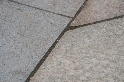 Several cracks between blocks of concrete sidewalk. Some are perpendicular an Stock Photos