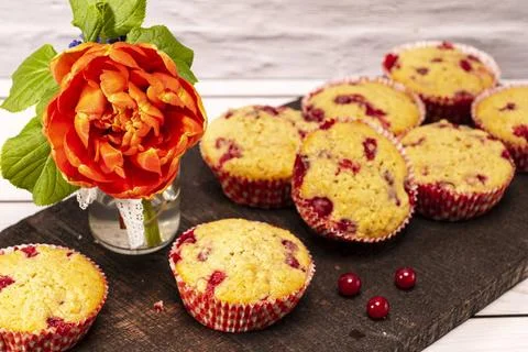 Several currants muffins served on an old wooden board with bouquet of flo... Foto stock
