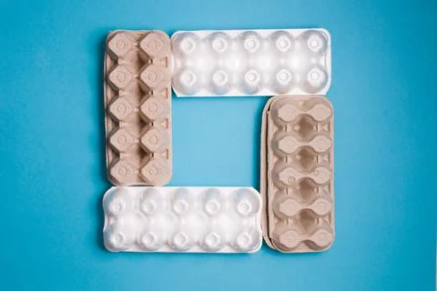 Several different boxes for eggs are laid out in a square on a blue backgroun Stock Photos