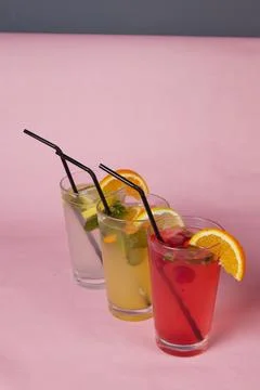 Several different drinks on table, lemonade in glass, slice of lemon and straws Stock Photos