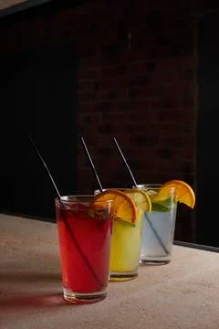 Several different drinks on table, lemonade in glass, slice of lemon and straws Stock Photos