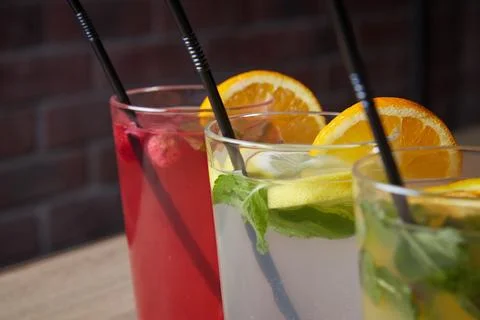 Several different drinks on table, lemonade in glass, slice of lemon and straws Stock Photos