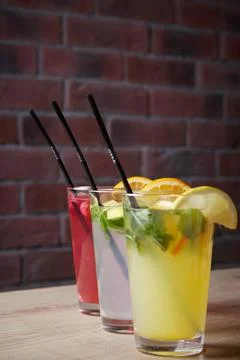 Several different drinks on table, lemonade in glass, slice of lemon and straws Stock Photos
