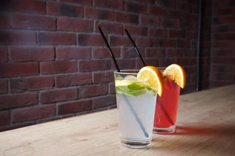 Several different drinks on table, lemonade in glass, slice of lemon and straws Stock Photos