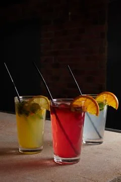 Several different drinks on table, lemonade in glass, slice of lemon and straws Stock Photos
