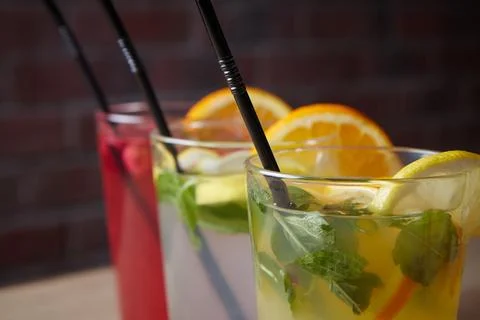 Several different drinks on table, lemonade in glass, slice of lemon and straws Stock Photos