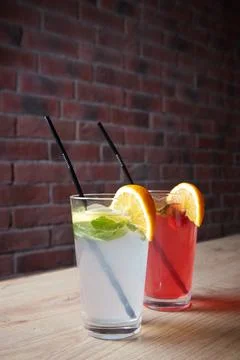 Several different drinks on table, lemonade in glass, slice of lemon and straws Stock Photos