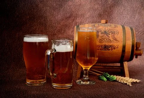 Several different glasses with light beer, a wooden keg, ears of wheat and ho Stock Photos