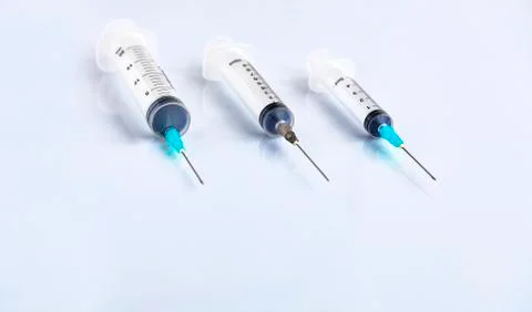 Several different syringes on a white smooth table, ready for use. Stock Photos