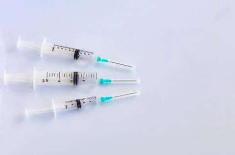 Several different syringes on a white smooth table are filled with mortar and Stock Photos
