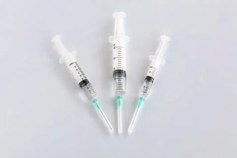 Several different syringes on a white smooth table are filled with mortar and Stock Photos